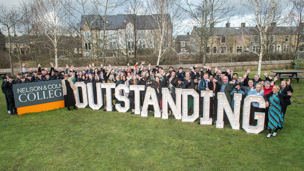 large group of students stood behind huge letters spelling OUTSTANDING