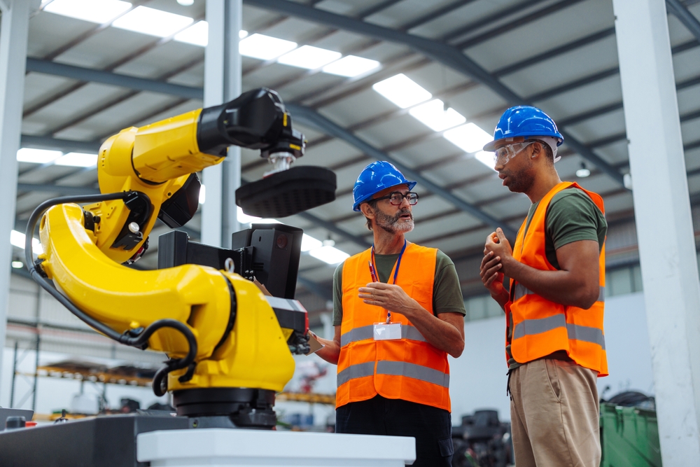 Two,Engineers,Discussing,The,Performance,Of,A,Robotic,Arm,In